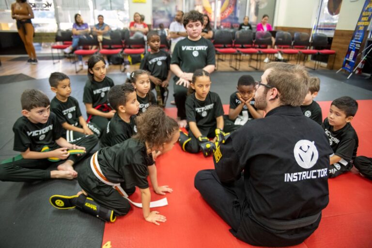 Karate Instructor Siting on the Gym Floor Surrounded by Kids in Maitland, FL