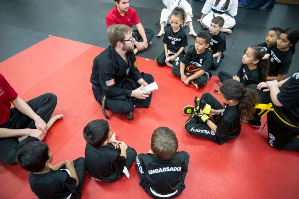 Karate Instructor Siting on the Gym Floor Surrounded by Kids in Hunter's Creek, FL