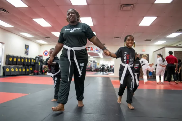 Female Instructor Holding Hands of Two Children at Kids' Self-Defense Classes in Dr. Phillips, Florida